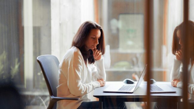 Student werkt aan sollicitatie overheid Student verdiept zich in stage of traineeship bij de overheid op laptop, zittend aan bureau in rustige werkomgeving