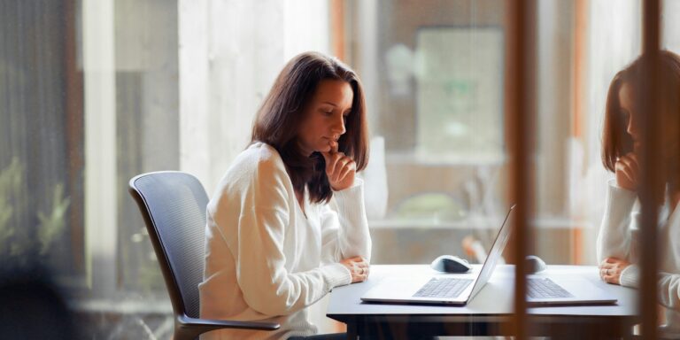 Student verdiept zich in stage of traineeship bij de overheid op laptop, zittend aan bureau in rustige werkomgeving